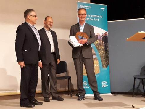 De overhandiging van de vlag. Op de foto van links naar rechts: Peter Clements van Kangaroo Island, president van ISISA Godfrey Baldacchino enklaas Deen, secretaris van de Waddenacademie.