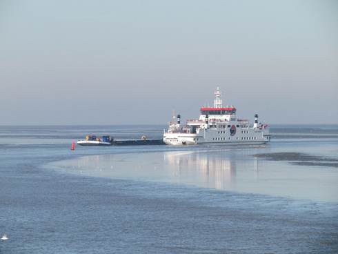 De veerboot naar Ameland passeert een baggerschip in de vaargeul. Foto: Thea Smit