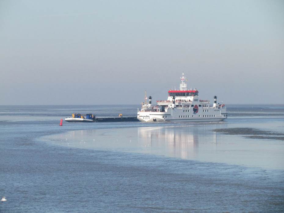 Een baggerschip passeert de veerboot naar Ameland. Foto: Thea Smit