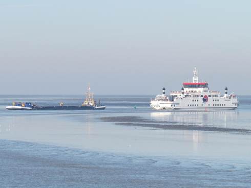 Een baggerschip en veerboot passeren elkaar op de Waddenzee in de vaargeul naar Ameland
