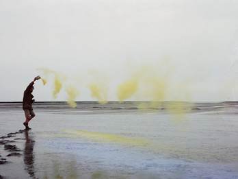 Kunstenaar Han Jansen strooit geel pigment in de Waddenzee voor een tijdelijk kunstwerk. Foto John Stoel