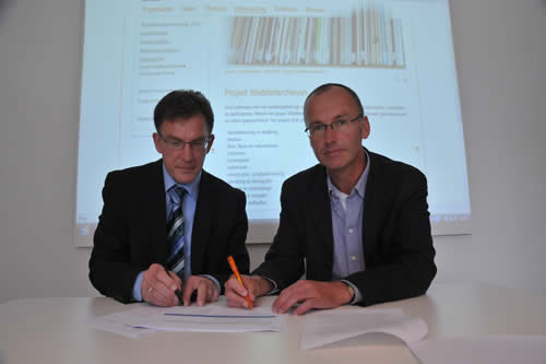 Bert Looper (directeur Tresoar) en Klaas Deen (bestuurssecretaris Waddenacademie) bezegelen de overdracht. Foto: Haye Bijlstra